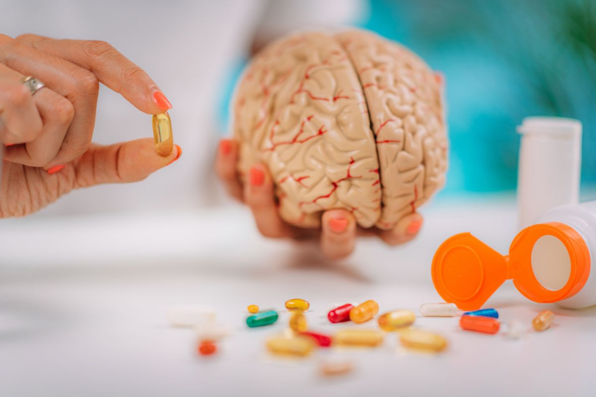 Cognitive improvement or brain supplements. Woman holding a supplement capsule and a model brain